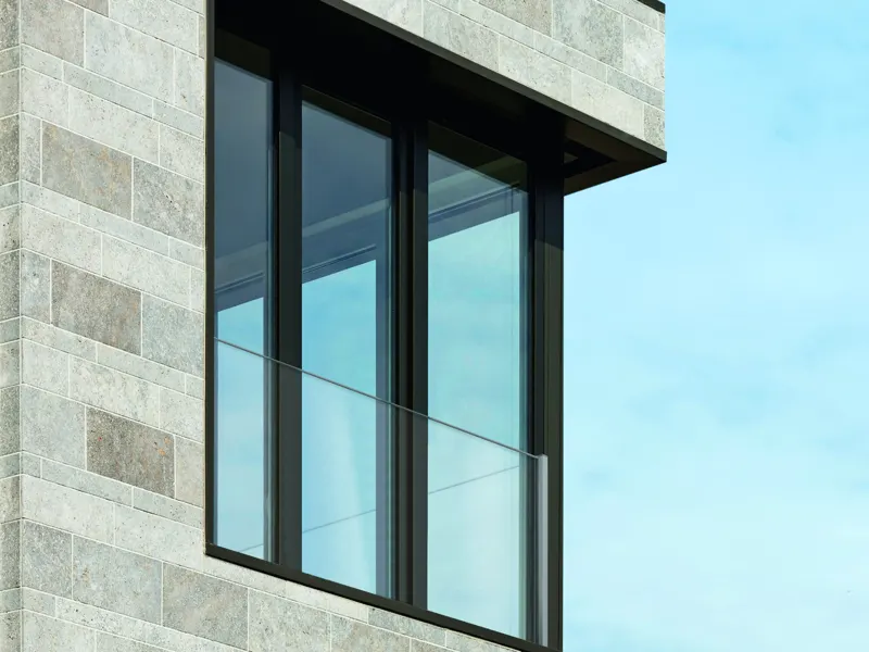 Floor-to-ceiling dark-framed windows with frameless glass fall protection on a stone facade
