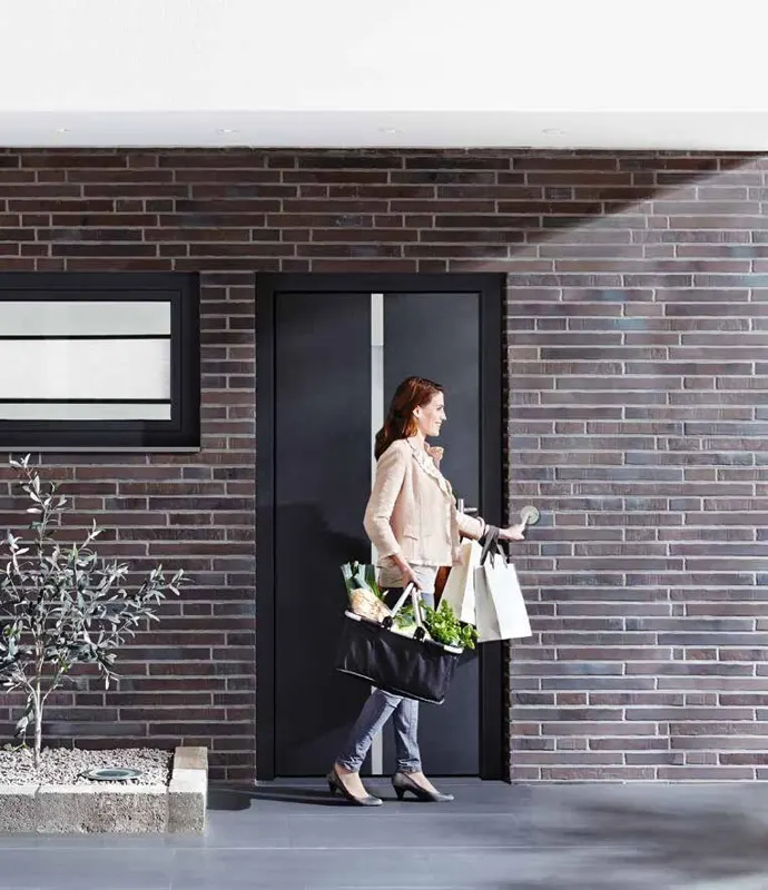 Dark Schueco uPVC entrance door with sidelight in a dark brick facade