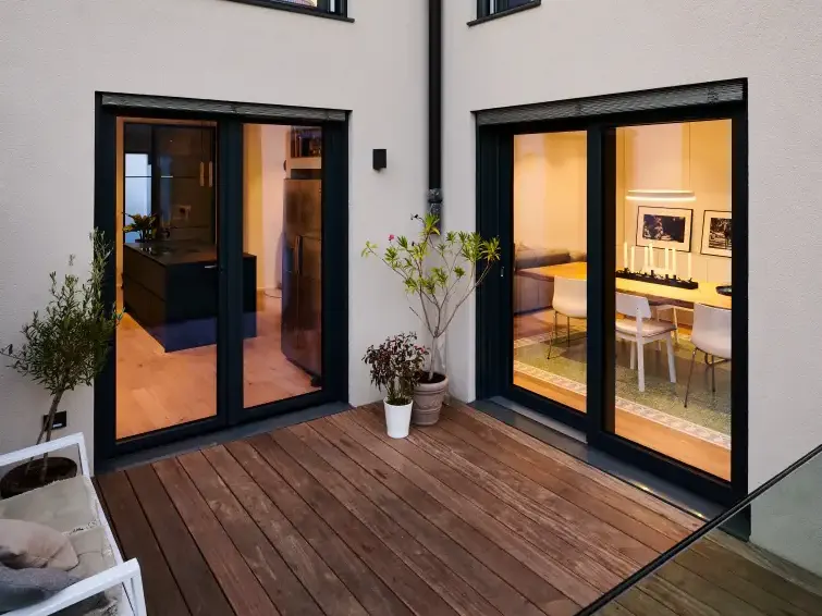 Two pairs of dark uPVC French doors opening onto a timber deck