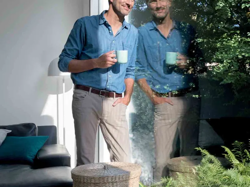 Two people with coffee mugs at a large uPVC window looking out to a garden